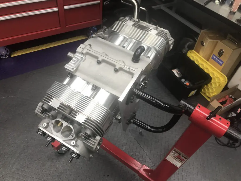 A shiny metallic engine block on a red stand in a workshop.