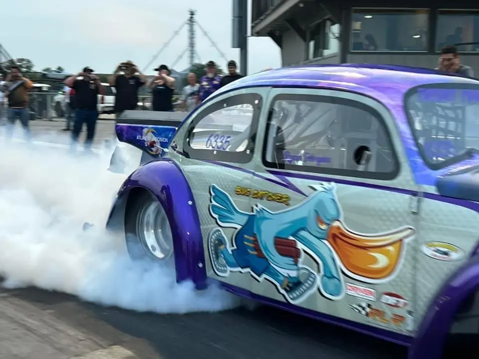 A customized car with colorful artwork performing a burnout.