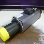 Close-up of a mechanical actuator with a yellow cap and electronic components.