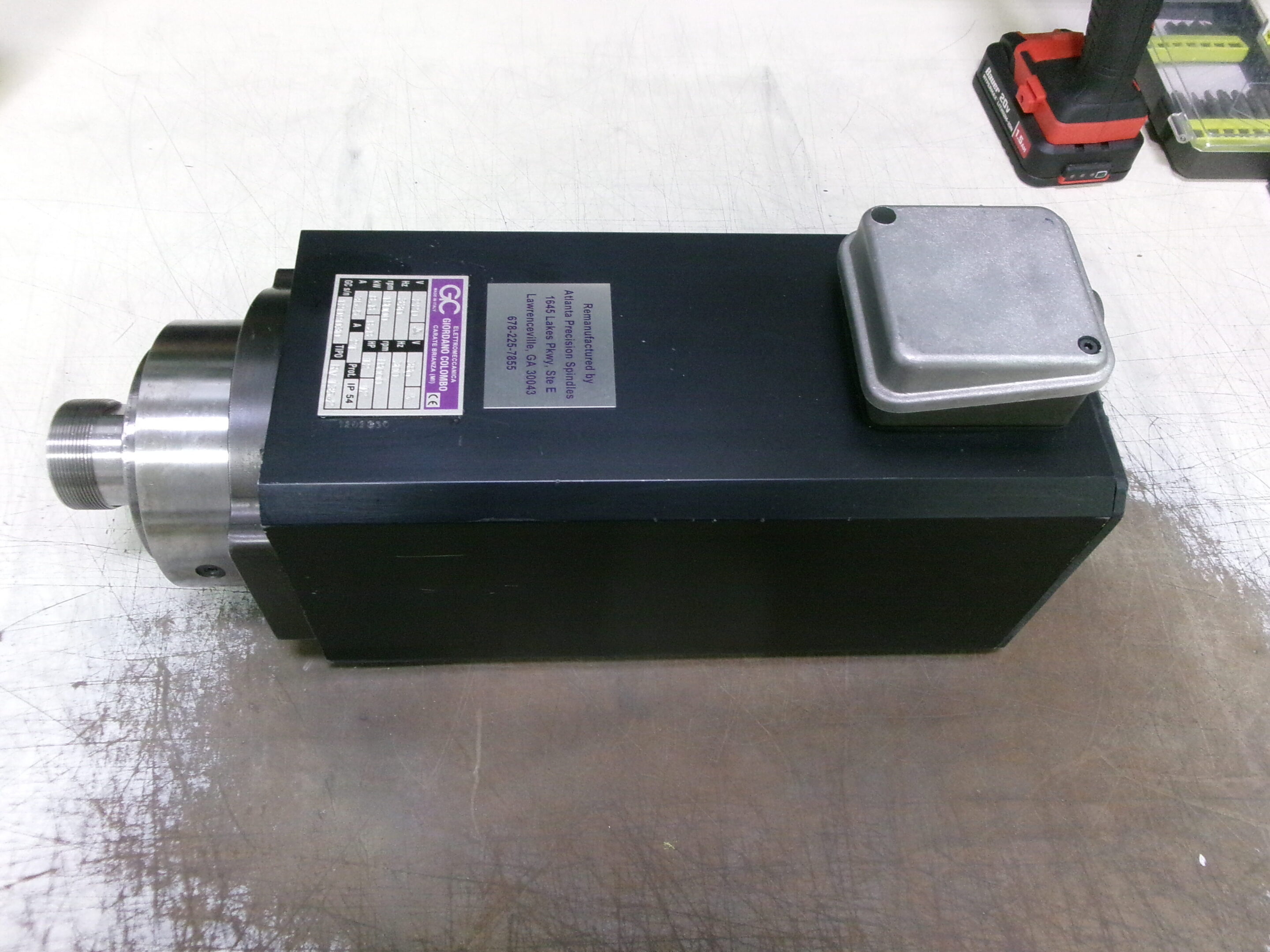 Industrial spindle motor with metal housing on a workshop floor.