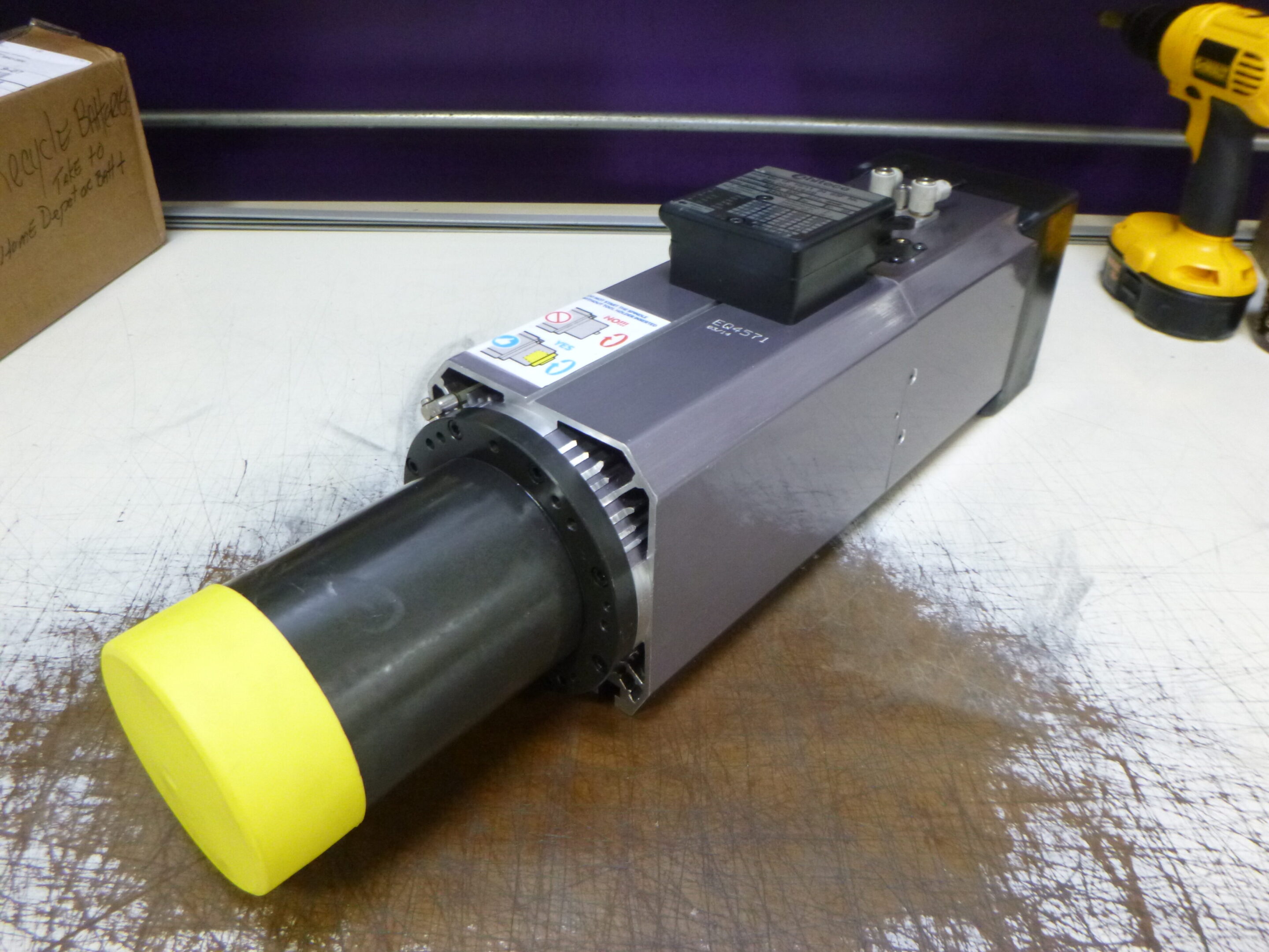 Close-up of a mechanical actuator with a yellow cap and electronic components.