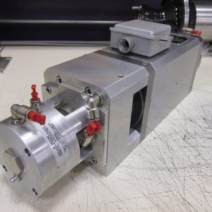 Metal industrial machine component with red valves on a workbench.